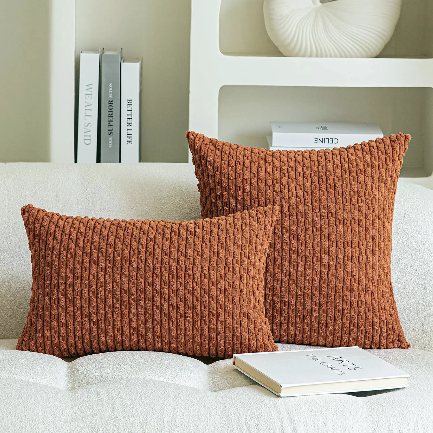 Two plush rust-colored corduroy cushion covers on a modern white sofa, enhancing home comfort and style.