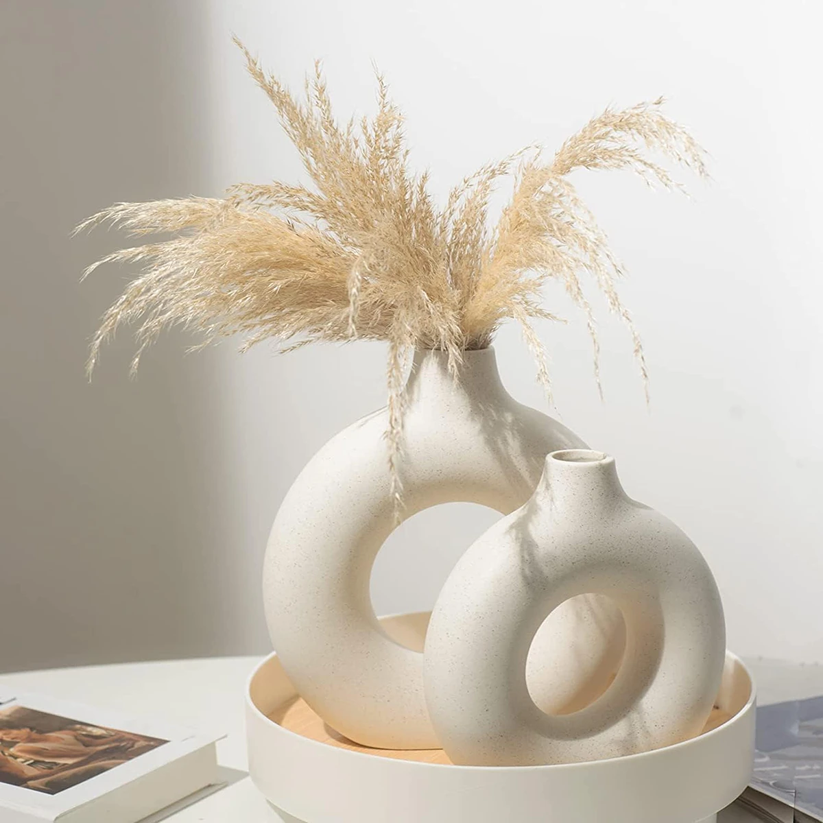 White ceramic donut-shaped vase adorned with fluffy pampas grass, creating a blend of modern style and natural texture.