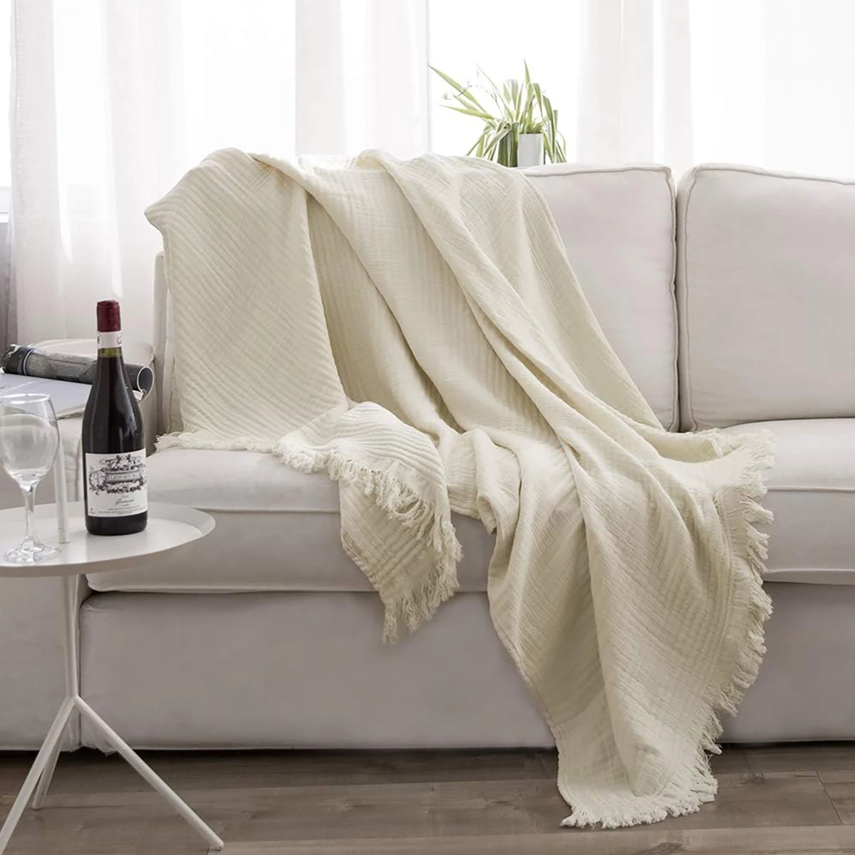 Luxurious cotton muslin throw blanket draped over a couch, complementing the modern home decor with its natural gauze cotton texture.